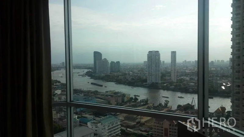 Condominium for rent in Sathon, Bangkok - Panoramic city and river view framed by a large condo window.