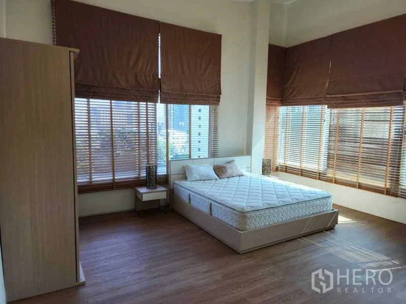 公寓 出租在Phaya Thai, Bangkok - 转角主卧，环窗设计与温润木地板。