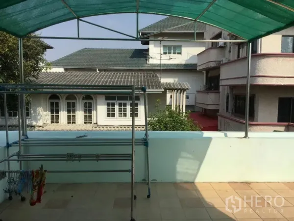 独立式住宅 出租或出售在Huai Khwang, Bangkok - 带绿色遮阳篷的屋顶露台，设晾衣架，可眺望邻屋。