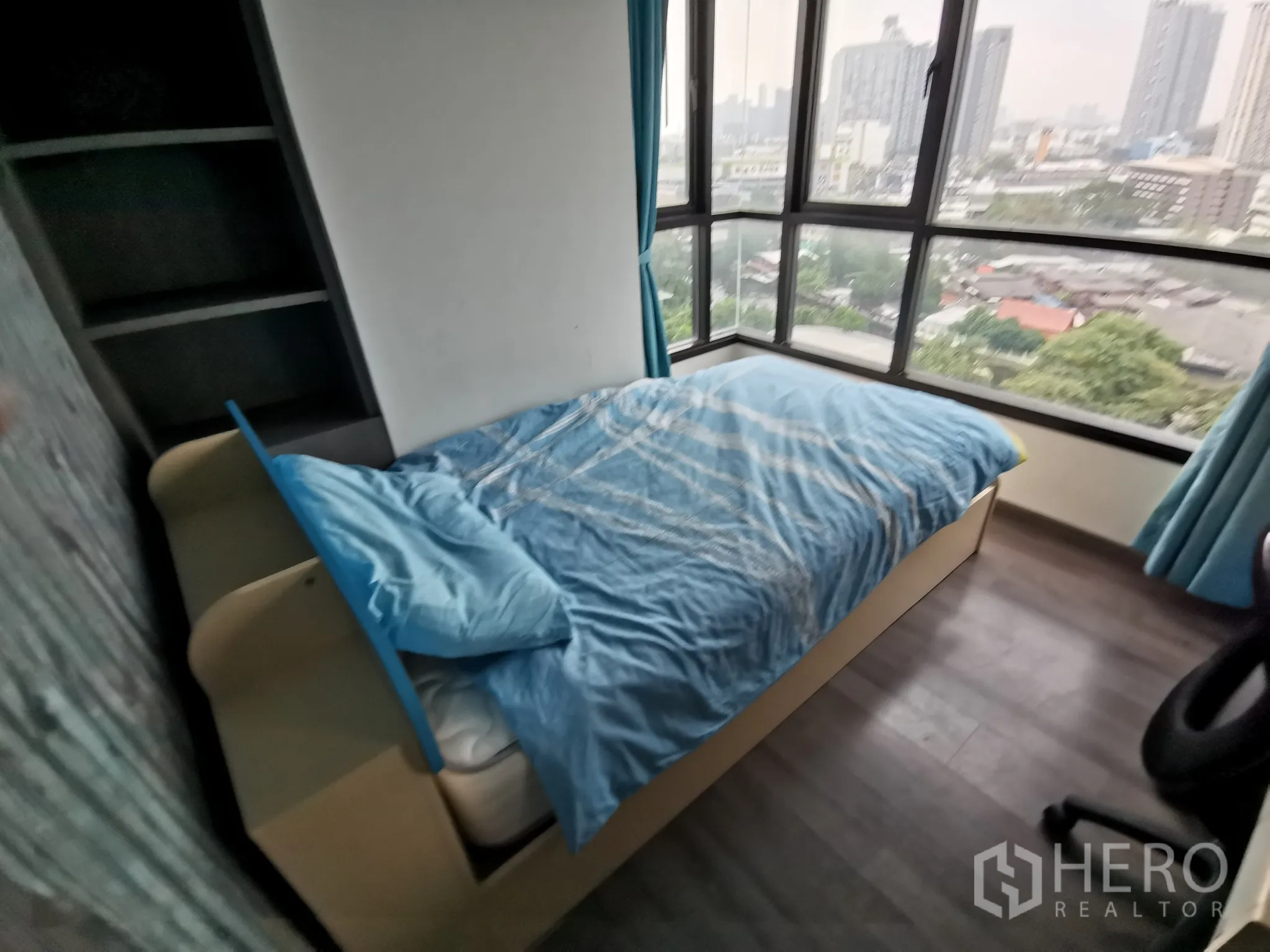 Condominium for rent or sale in Watthana, Bangkok - Corner bedroom with panoramic windows and single bed facing the city skyline.