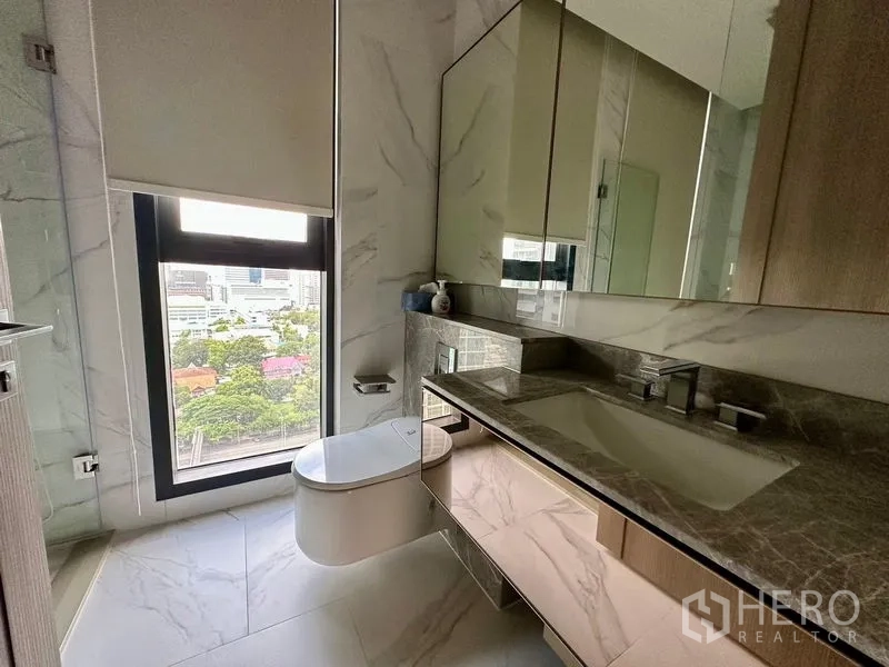 Condominium for rent - Bathroom vanity with stone countertop, mirrored cabinets, and a window offering a city view.