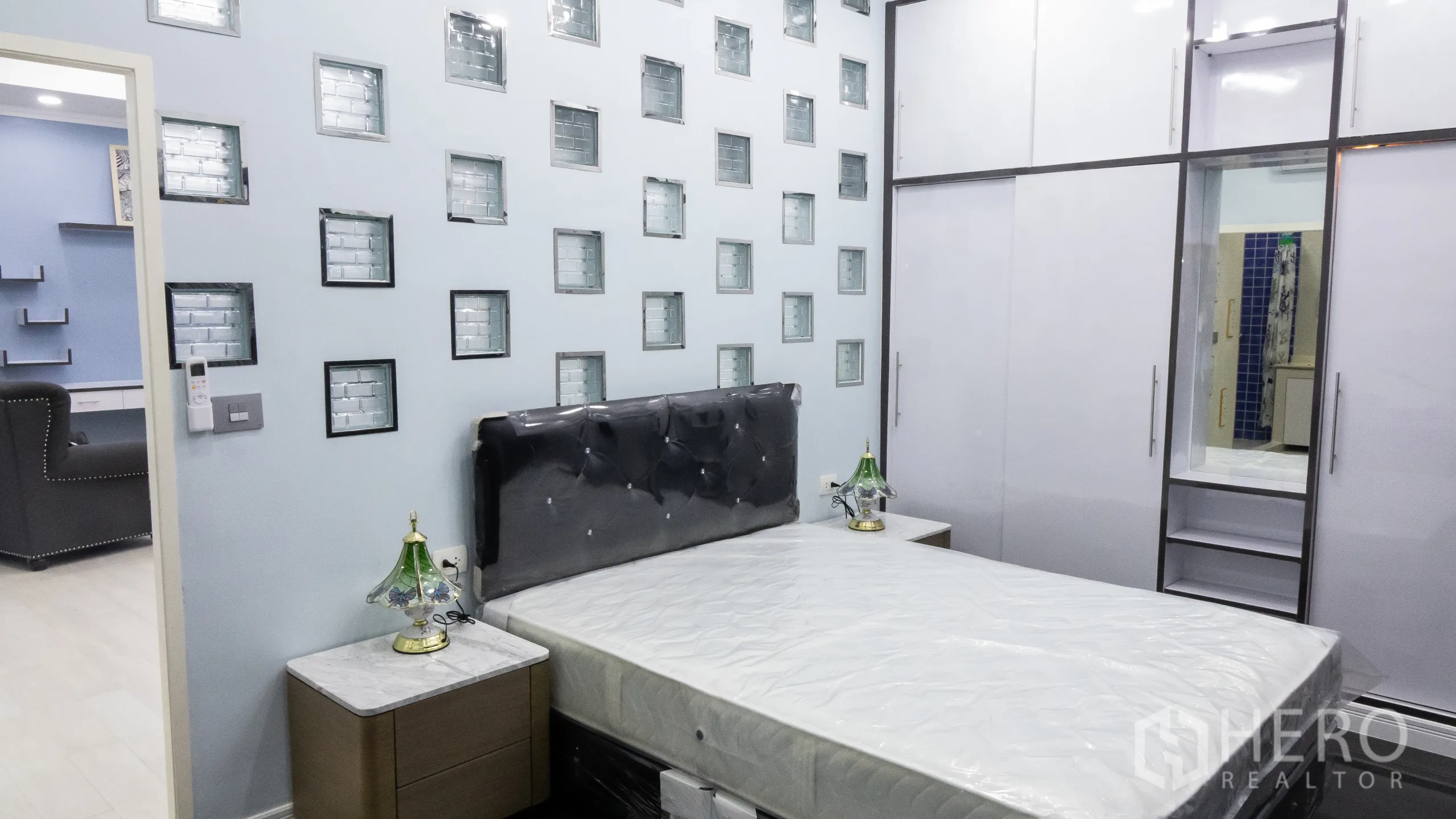 Condominium for rent or sale in Khlong Toei, Bangkok - Bedroom with bed, glass‑block wall detailing and floor‑to‑ceiling wardrobes.