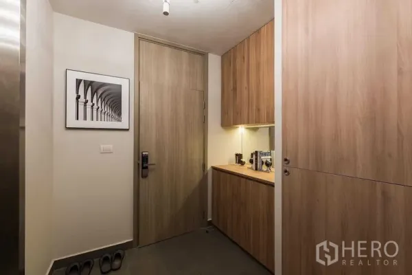 Condominium for rent in Pathum Wan, Bangkok - Entry hallway featuring built‑in wood cabinets, countertop and framed artwork.