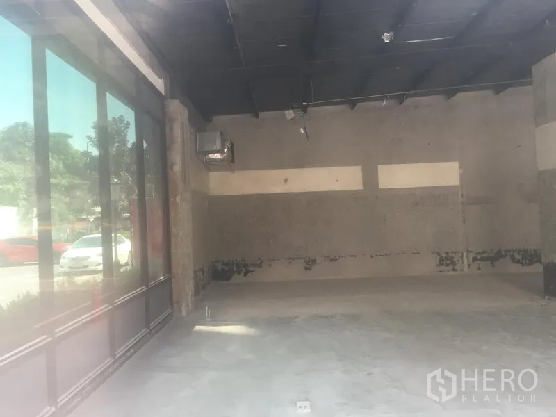 零售空间 出租在Khlong Toei, Bangkok - 开放式空置商铺，挑高黑色吊顶与水泥地面。