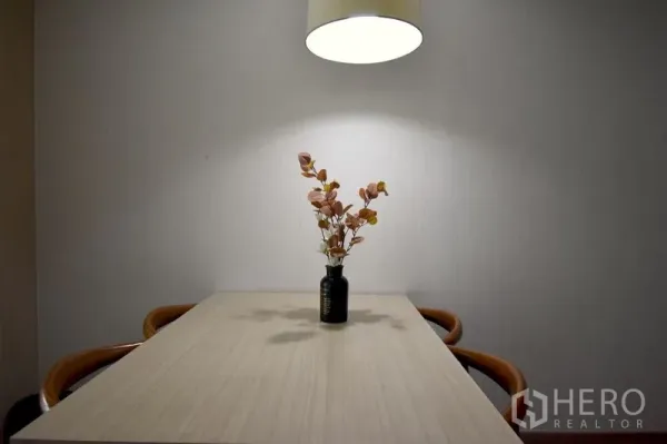 Condominium for rent in Khlong Toei, Bangkok - Minimalist dining table with a pendant light and a small vase centerpiece.