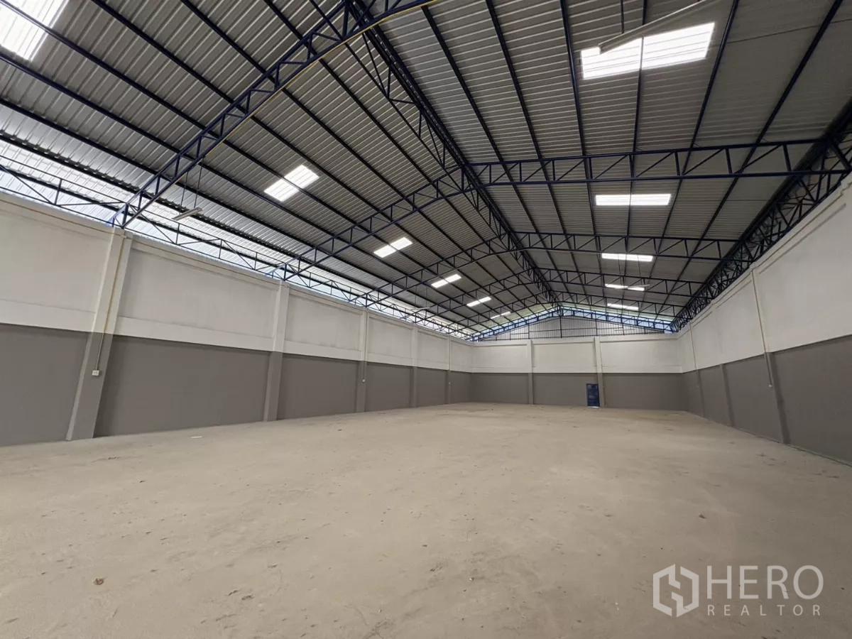 Warehouse for rent in Mueang Samut Prakan, Samut Prakan - Open industrial space with a high ceiling, LED panels and smooth concrete floor.