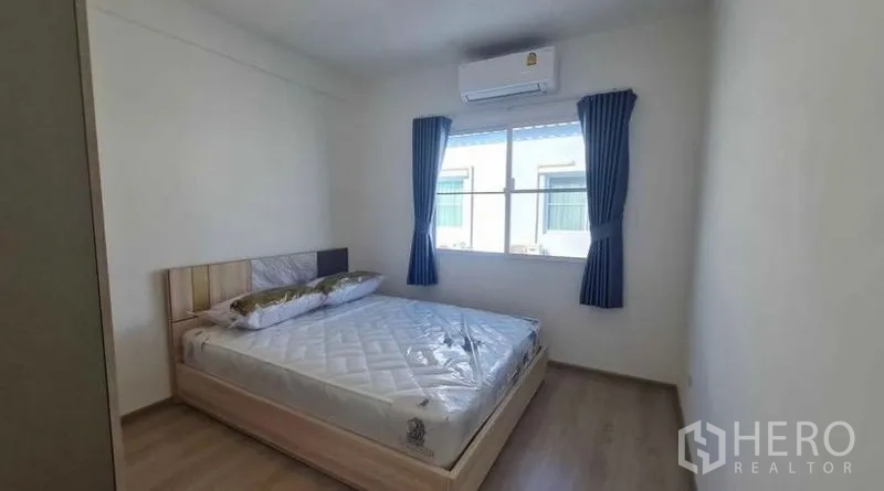 Townhouse for rent in Prawet, Bangkok - Cozy second bedroom with double bed, window and wall-mounted air conditioner.