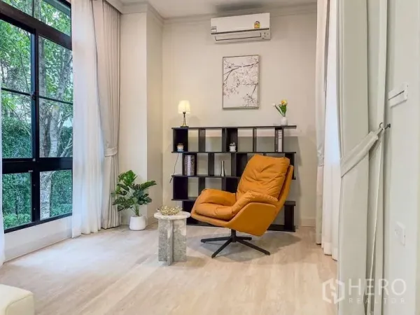 Detached House for rent in Saphan Sung, Bangkok - Sunlit reading corner with large black-framed windows, bookshelf and mustard lounge chair.
