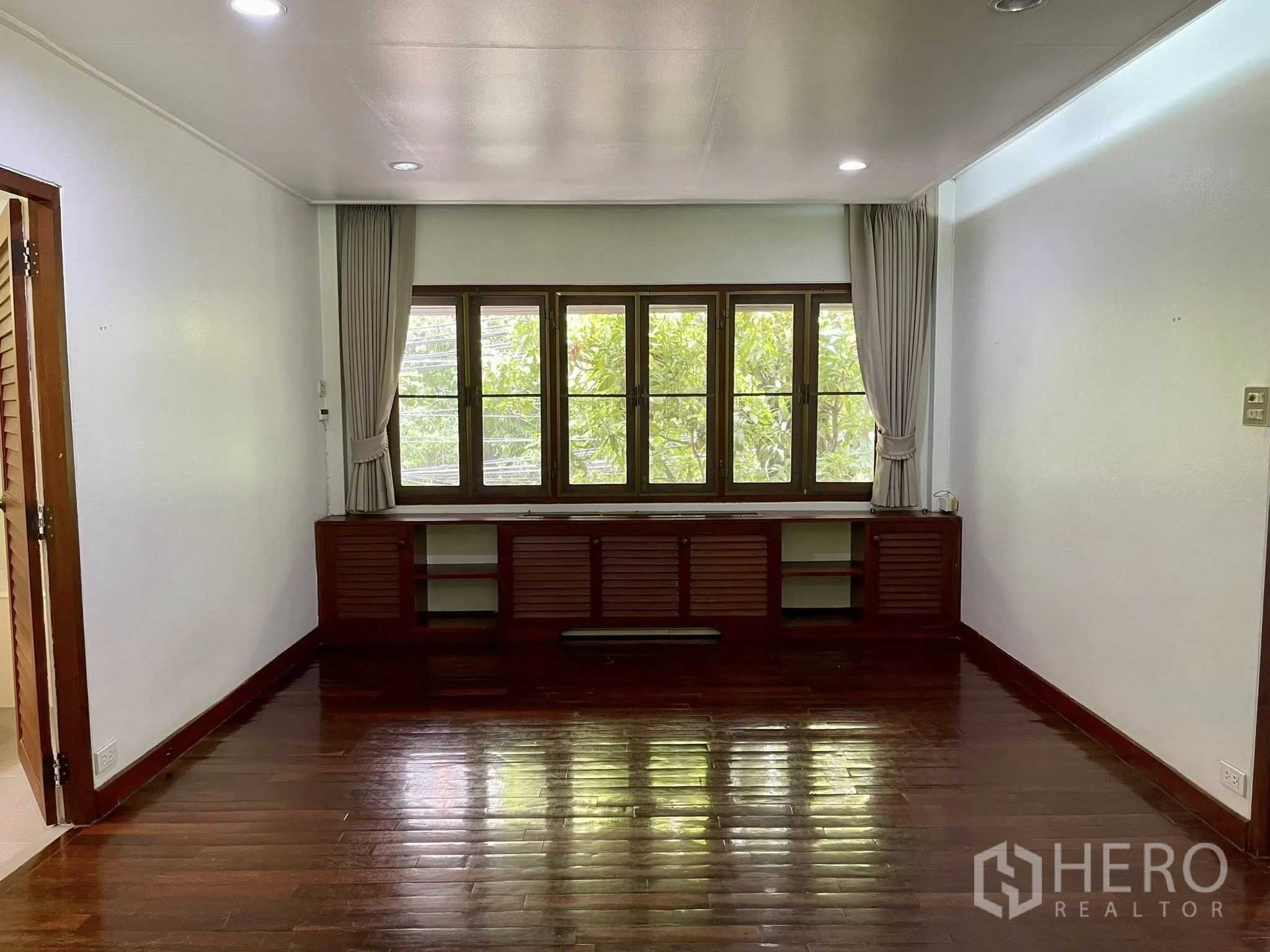 Detached House for rent in Pathum Wan, Bangkok - Bedroom with low built-in cabinetry under the windows and curtains.