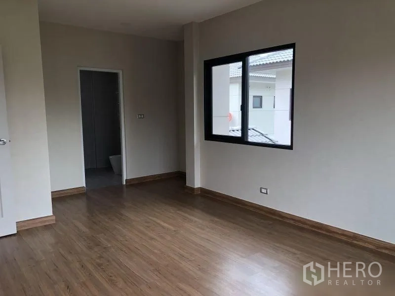 Detached House for sale in Bang Phli, Samut Prakan - Master bedroom with wood floors and doorway to ensuite bathroom