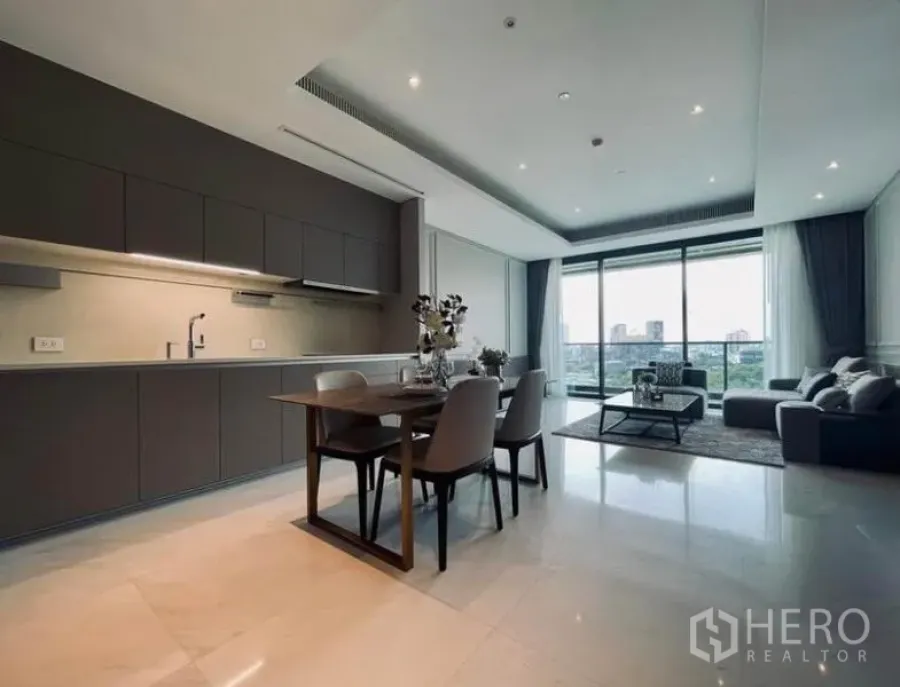 公寓 出租在Pathum Wan, Bangkok - 开放式客餐厅与灰色一字型厨房，仿石地面，带阳台城市景观，位于巴吞旺区公寓内。