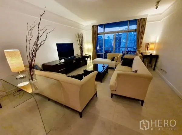 Condominium for sale in Pathum Wan, Bangkok - Spacious living room with cream sofas, TV console and balcony city view at dusk