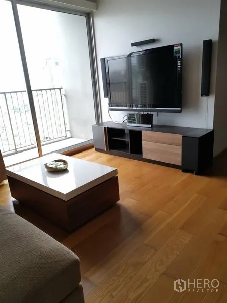 公寓 出租在Khlong San, Bangkok - 电视柜与平板电视，旁为推拉阳台门和木地板。