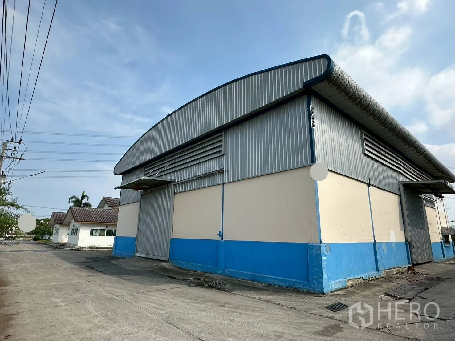 Factory for rent in Lat Lum Kaeo, Pathum Thani - Corner view of blue and cream factory building with corrugated metal cladding in a secure compound.