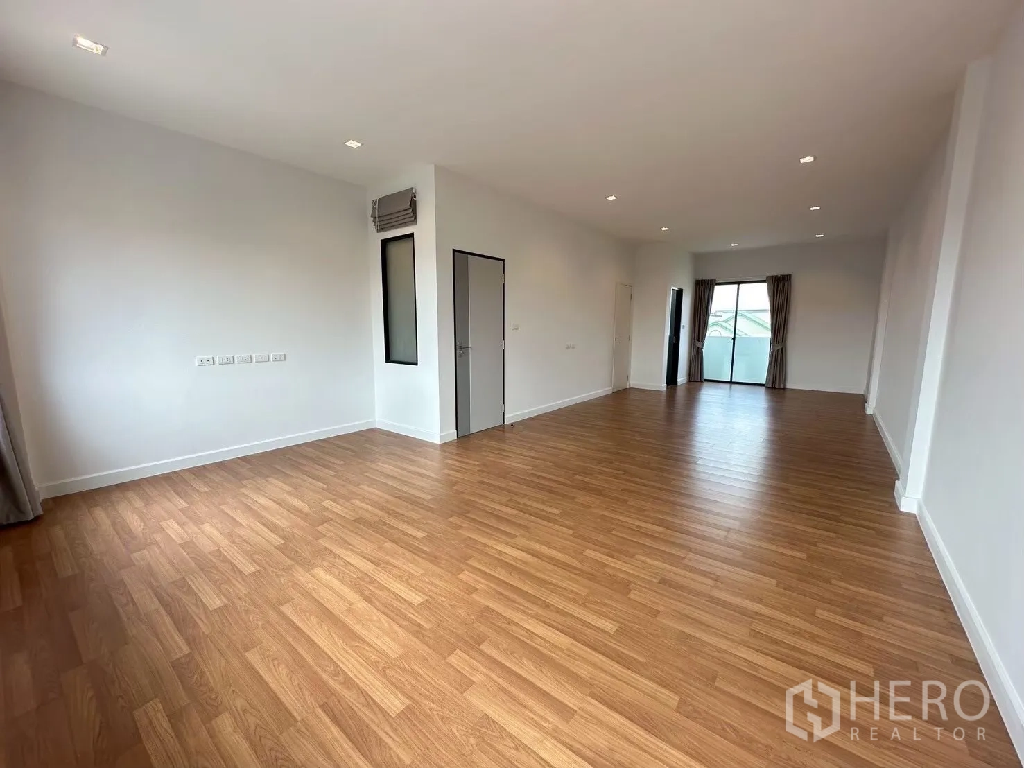 Home Office for rent in Lat Phrao, Bangkok - Long multi-purpose room with wood floors and sliding doors to balconies at both ends.