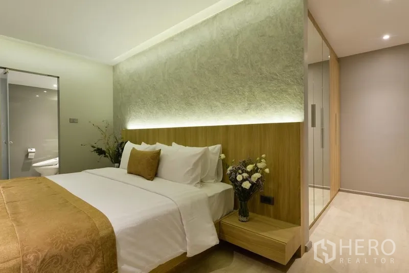 房间 出租在Khlong Toei, Bangkok - 温馨卧室，发光床头墙与花艺装饰，并连接套内卫生间