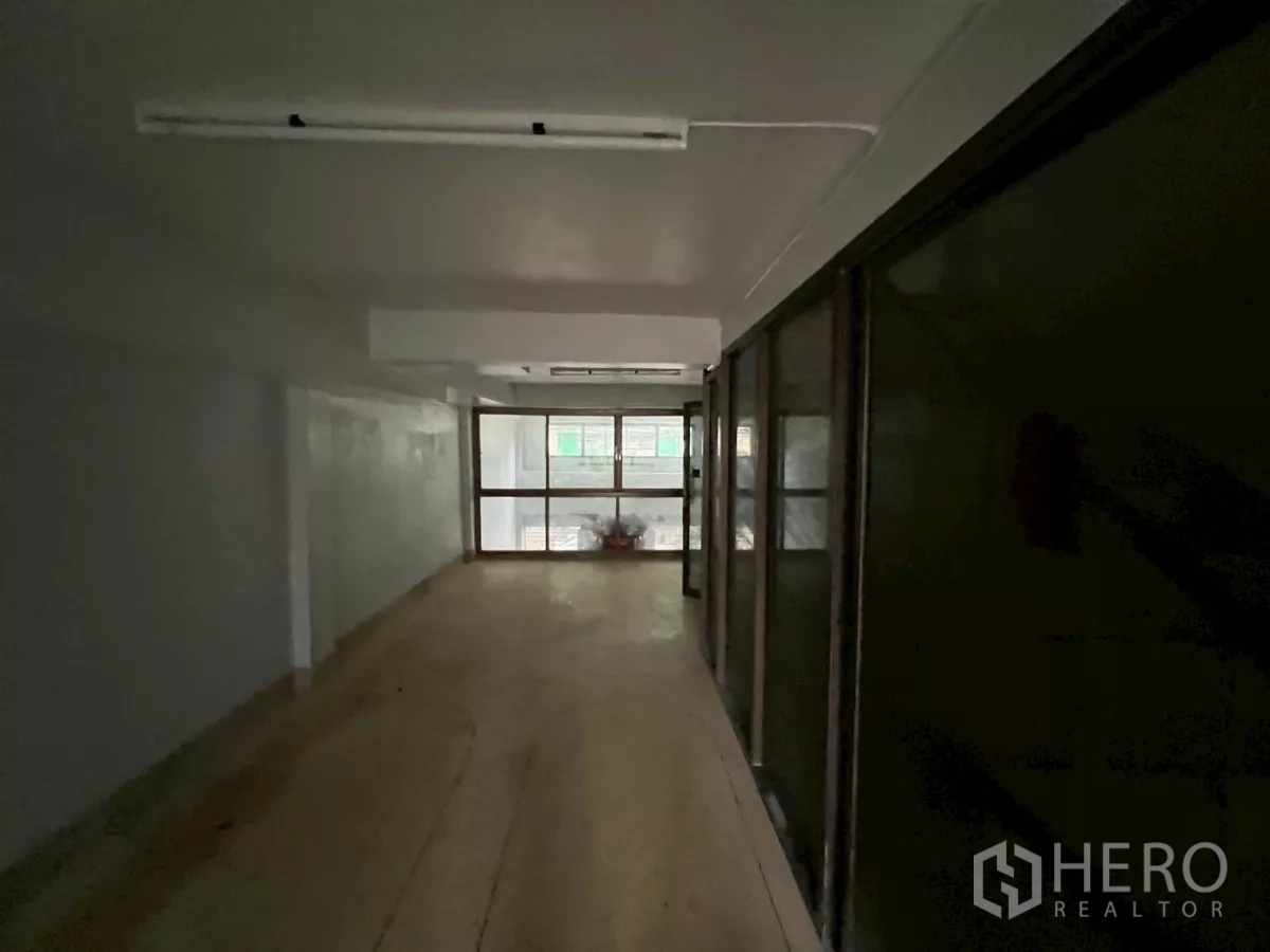 Shophouse for rent in Khlong Toei, Bangkok - Deep corridor-like room with sliding partitions and a window at the far end.