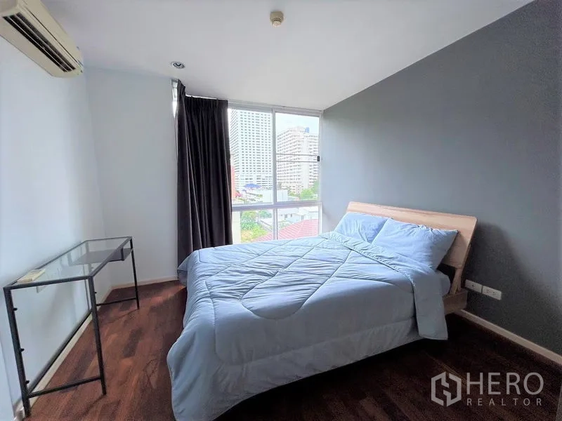 Condominium for rent or sale in Khlong Toei, Bangkok - Second bedroom with large window, double bed, and city outlook.