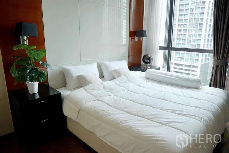 Condominium for rent or sale - Light-filled bedroom with a king bed and large windows overlooking the city.