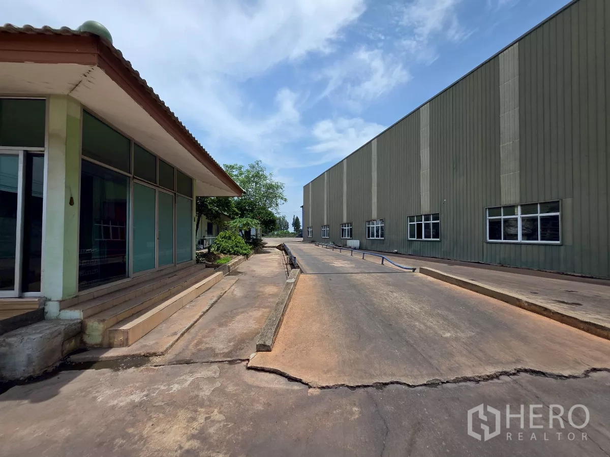 โรงงาน ให้เช่าในMueang Samut Sakhon, Samut Sakhon - ทางเข้าระหว่างอาคารสำนักงานกระจกกับอาคารโรงงานเมทัลชีตขนาดใหญ่พร้อมทางลาด