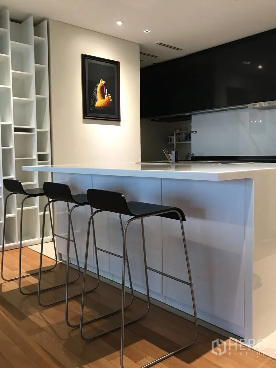 Condominium for rent in Khlong Toei, Bangkok - Contemporary kitchen with white island breakfast bar, storage and bar stools.