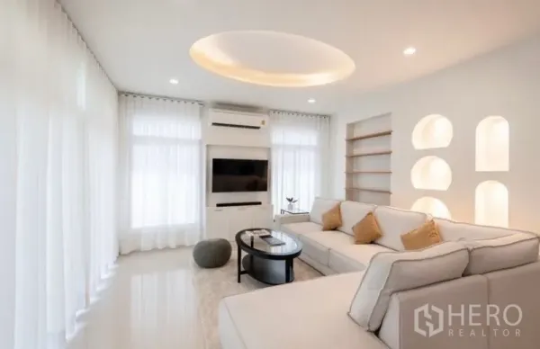 Detached House for rent or sale in Saphan Sung, Bangkok - Sunlit living room with white L-shaped sofa, TV wall, and arched display niches.