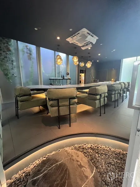Retail Space for rent in Khlong Toei, Bangkok - Lounge seating around a central curved counter with a zen rock feature and warm ambient lighting.