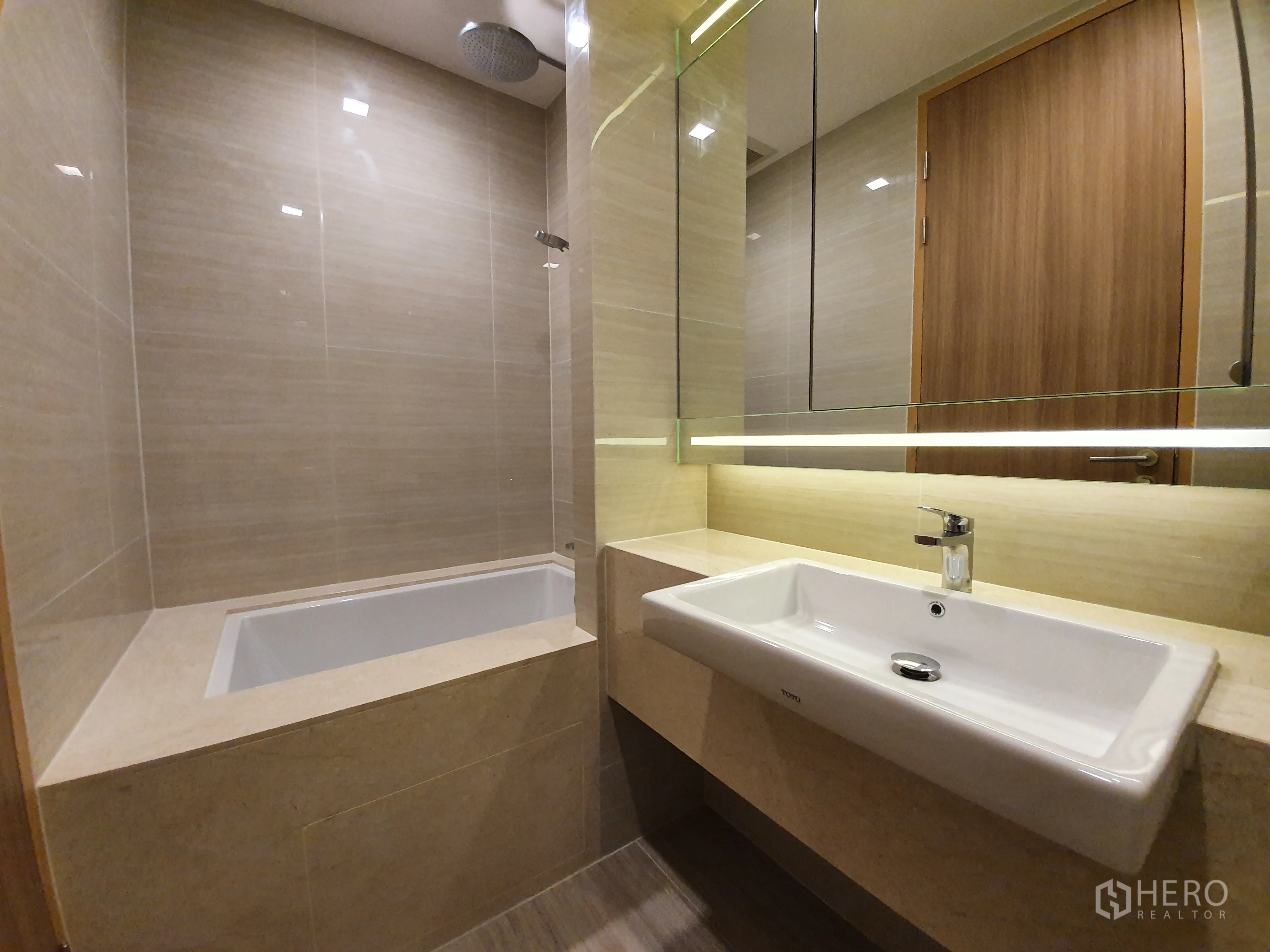 Condominium for rent in Watthana, Bangkok - Bathroom featuring a built-in soaking tub beside a wide countertop and illuminated mirror.