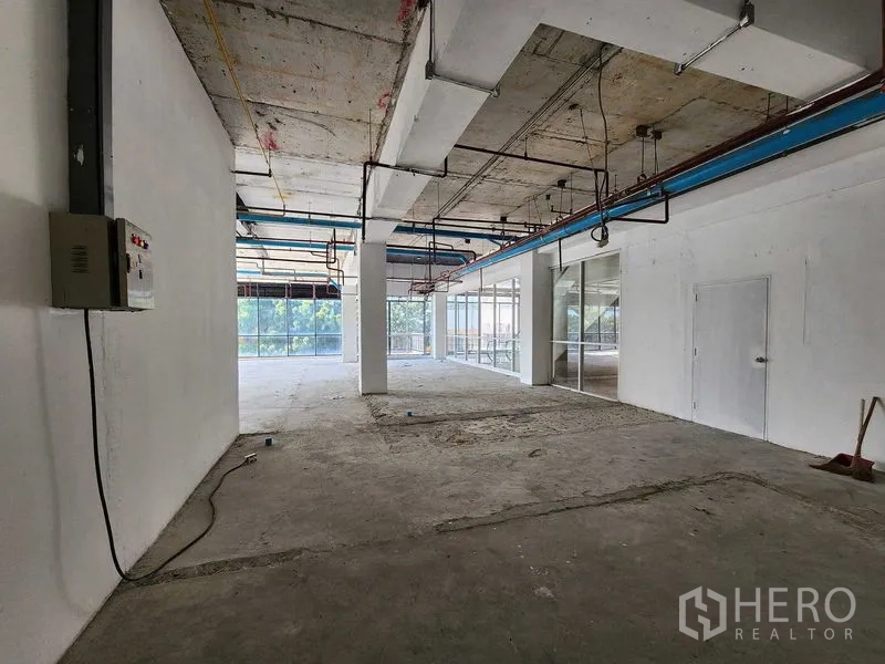 零售空间 出租在Sathon, Bangkok - 未装修的零售内景，有立柱、电控箱、后勤门与玻璃隔墙
