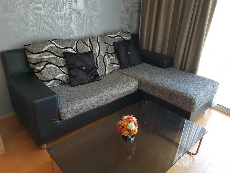 公寓 出租在Ratchathewi, Bangkok - 客厅配L型布艺沙发、玻璃茶几与落地窗帘。