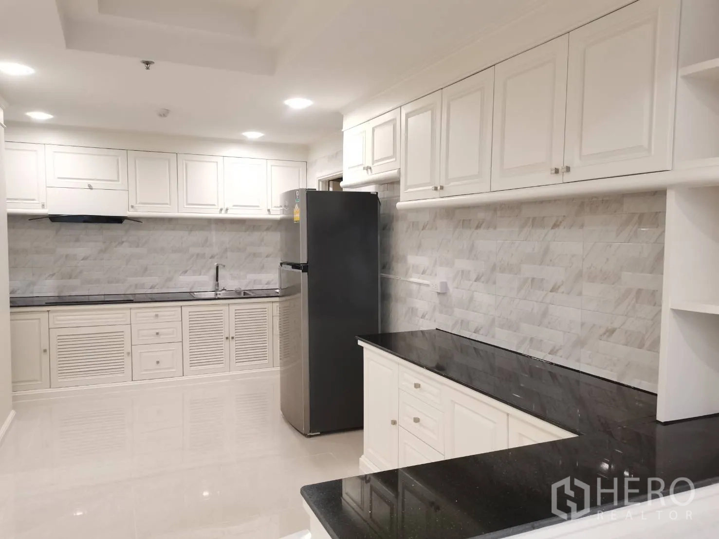 คอนโด for rent in Watthana, Bangkok - ครัวสว่างตา ตู้สีขาว ผนังลายหินอ่อน และท็อปหินสีดำพร้อมตู้เย็น