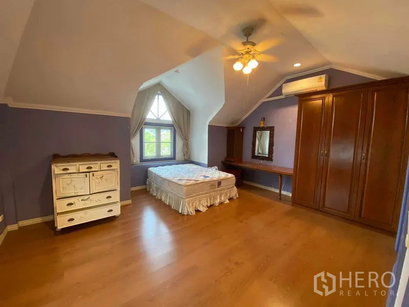 Townhouse for rent or sale in Mueang Samut Prakan, Samut Prakan - Top-floor bedroom with sloped ceiling, dormer window and wood floor.