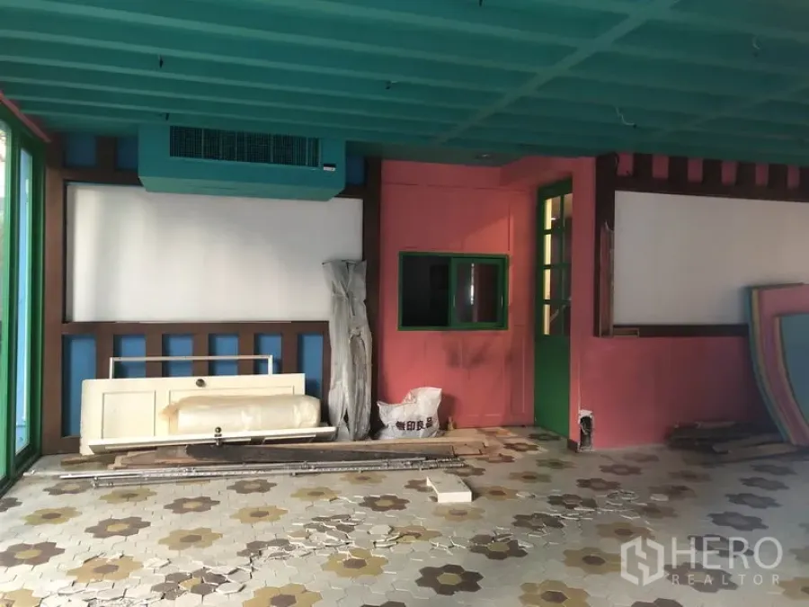 Retail Space for rent in Khlong Toei, Bangkok - Vacant retail interior with teal ceiling, pink walls, patterned tile floor and stored fit‑out materials.