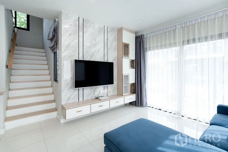 บ้าน ให้เช่าในBang Phli, Samut Prakan - ห้องนั่งเล่นสว่าง ผนังทีวีลายหินอ่อน บันได และผ้าม่านโปร่งสูงจรดฝ้า