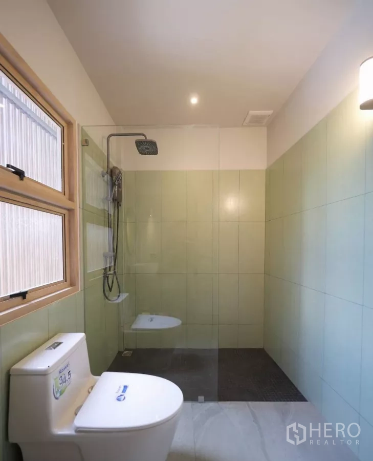 Townhouse for rent in Watthana, Bangkok - Bright bathroom with a glass-partition walk-in shower and window.