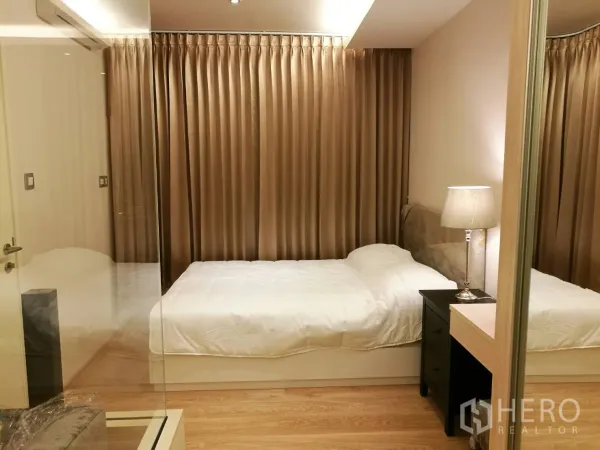 公寓 出租在Watthana, Bangkok - 温馨卧室，双人床、床头灯、落地窗帘与木地板。