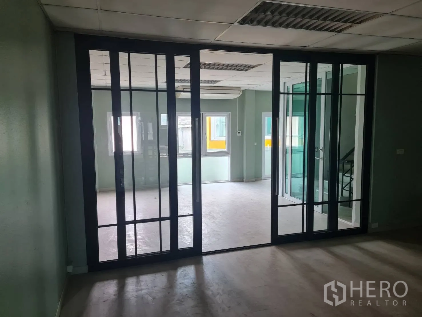 Warehouse for rent in Phra Pradaeng, Samut Prakan - Office area with framed glass sliding partitions and nearby staircase.