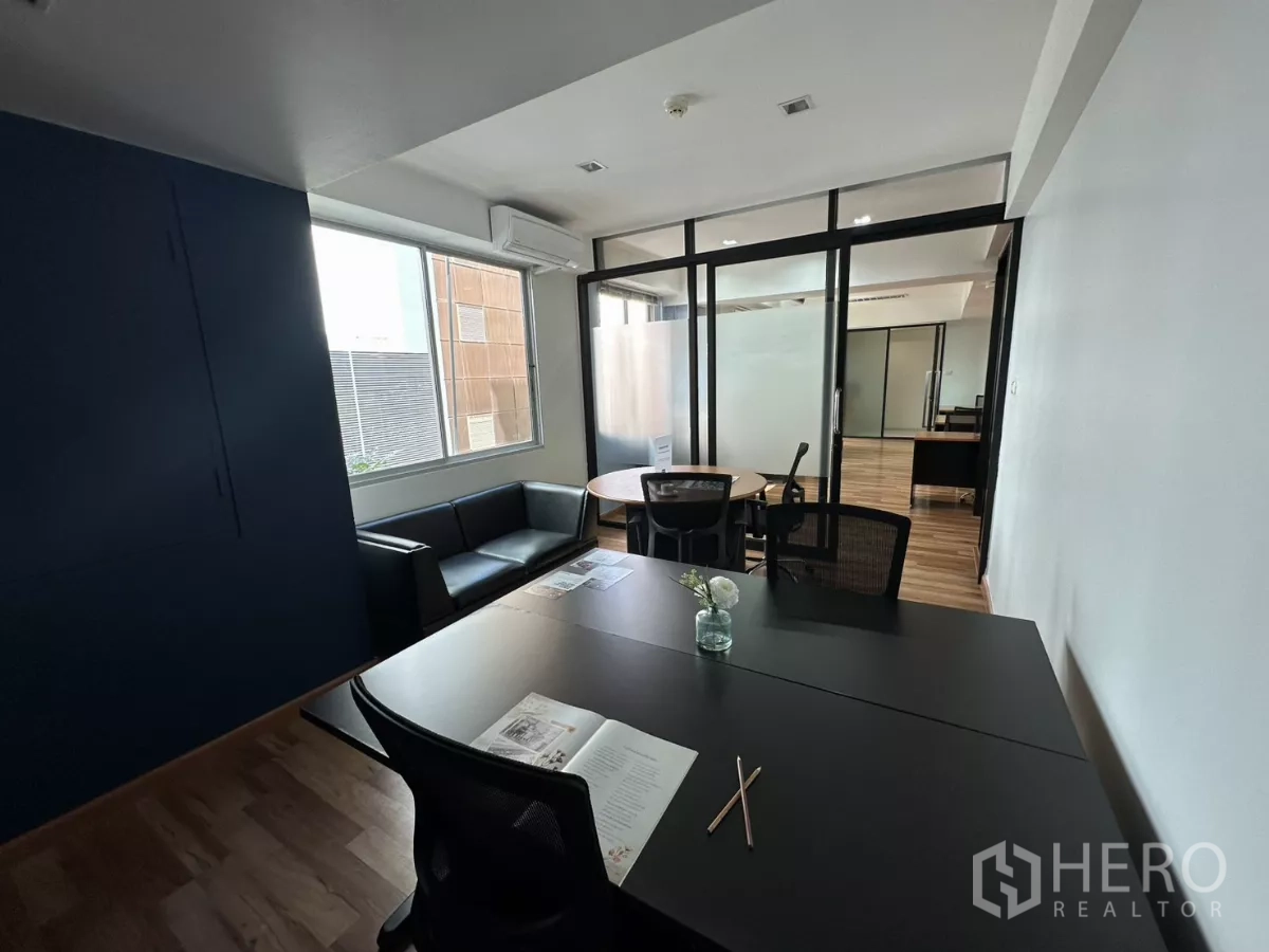 办公空间 出租在Watthana, Bangkok - 舒适工作角，深色桌面、小花瓶与磨砂玻璃隔断。