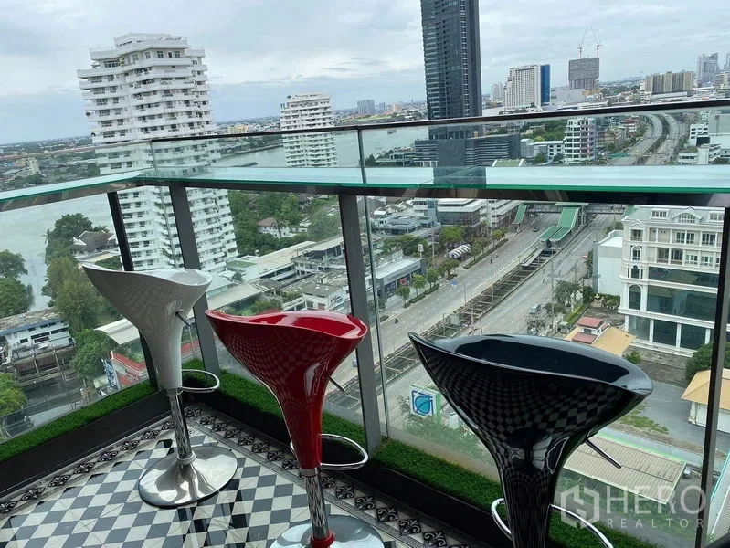 公寓 出售在Bang Kho Laem, Bangkok - 玻璃护栏阳台，吧凳俯瞰河景与天际线。