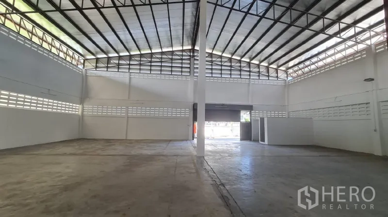 Warehouse for rent in Khlong Toei, Bangkok - High-clearance storage area with roller door and ventilated block walls.
