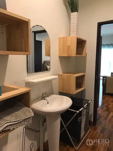 Townhouse for rent or sale in Phra Khanong, Bangkok - Powder room with pedestal sink, mirror and wooden storage shelves.