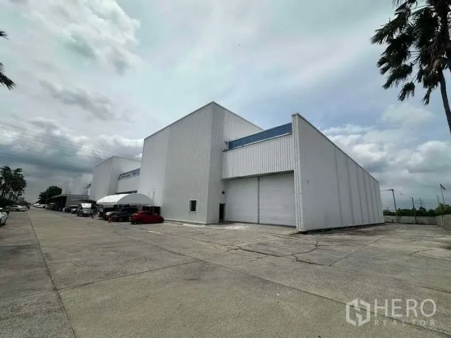 Factory for rent in Khlong Luang, Pathum Thani - Modern white factory exterior with large roller shutter and wide truck-friendly driveway in Khlong Luang.
