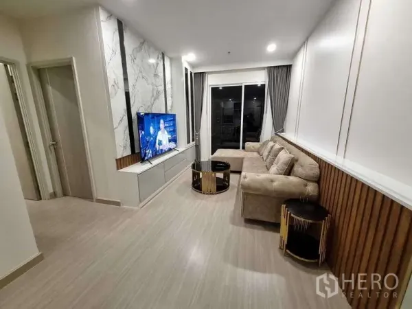Condominium for rent - Spacious living area with L-shaped sofa, TV unit and floor-to-ceiling sliding doors.