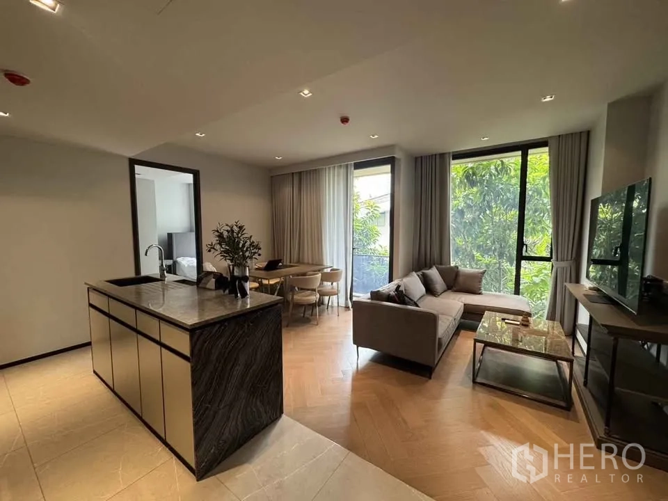 公寓 for rent in Watthana, Bangkok - 客餐厅一体，设中岛、沙发与圆餐桌，落地窗望绿景。