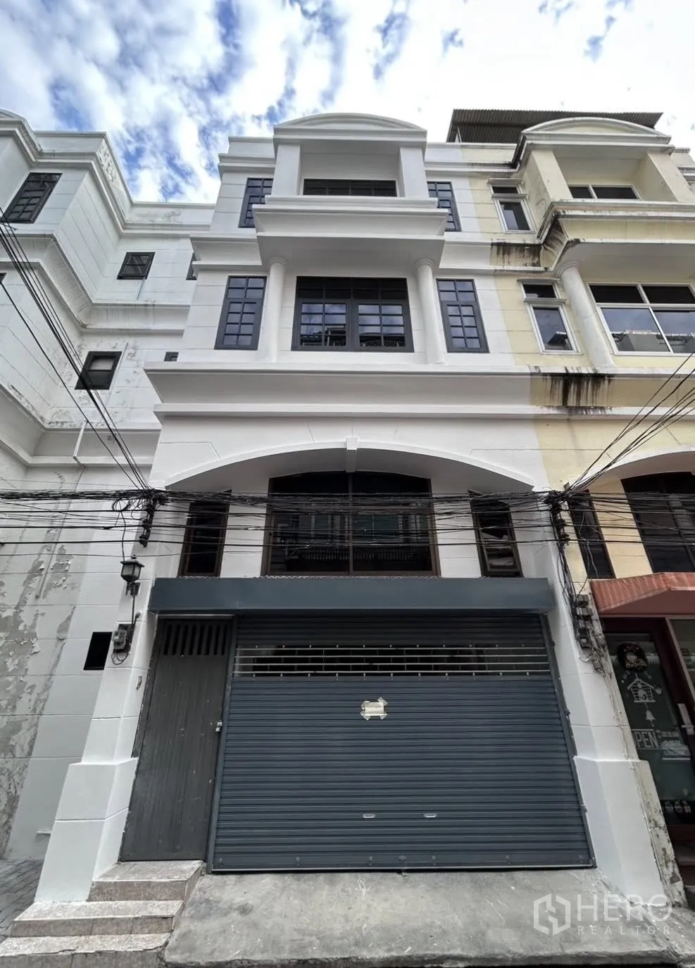 Home Office for rent or sale in Watthana, Bangkok - Multi-storey home office facade with arched balcony and roller shutter entrance.