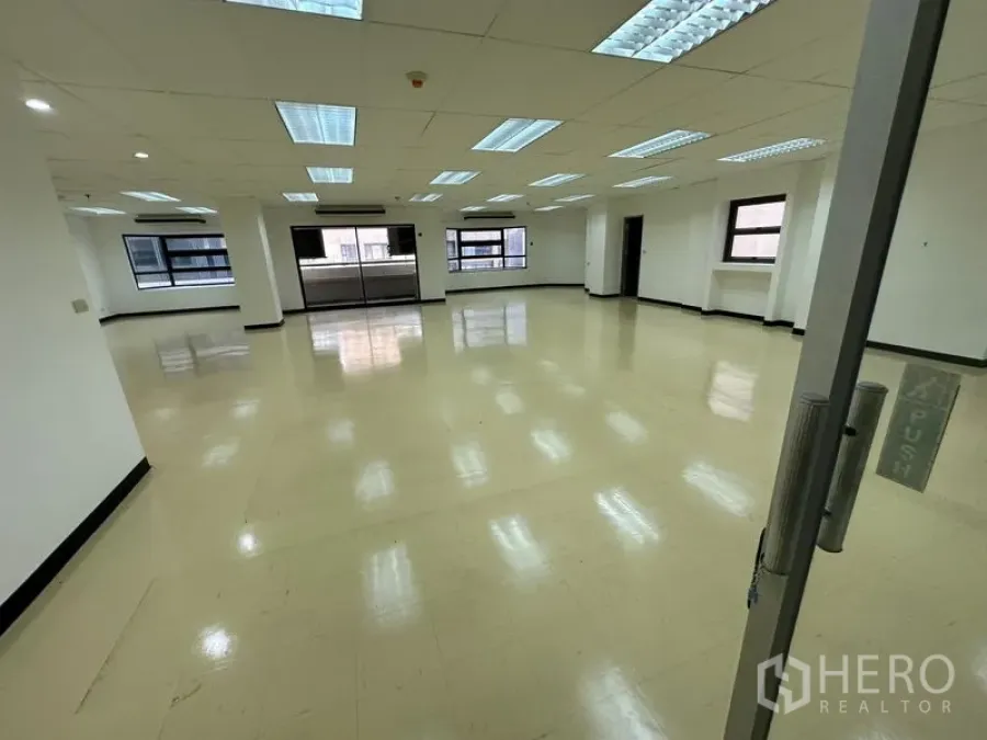 办公空间 出租在Pathum Wan, Bangkok - 从玻璃门入口望向开放式办公区，网格吊顶与多扇窗户。