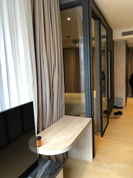 Condominium for rent in Din Daeng, Bangkok - Glass partition between living room and bedroom with curtains and light-wood finishes.