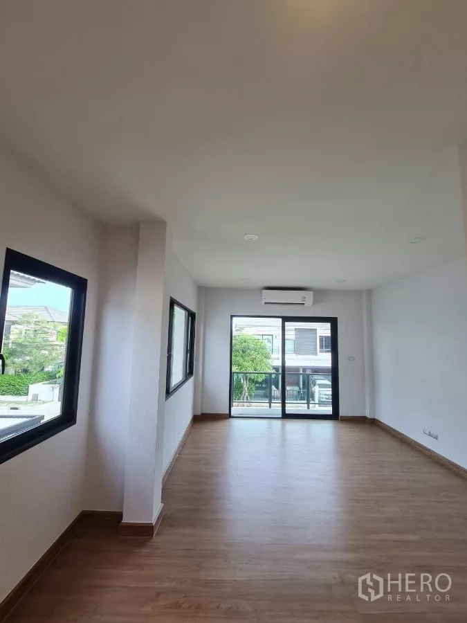 独立式住宅 出售在Samut Prakan - 明亮开放式起居空间，木质地板，多扇窗，推拉门通往阳台并配空调。