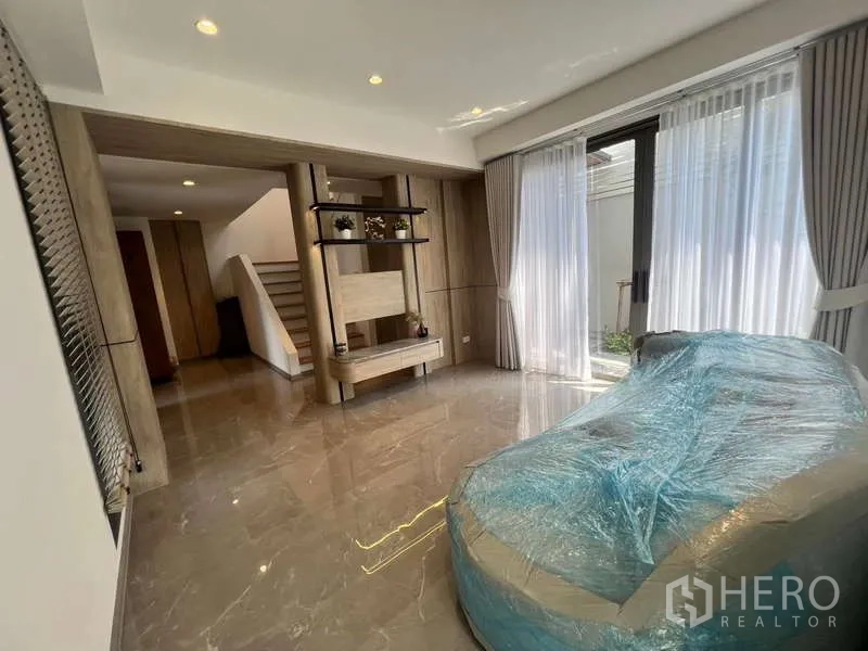 Townhouse for rent in Phra Khanong, Bangkok - Family room facing a private courtyard, with built-in shelving and staircase access.
