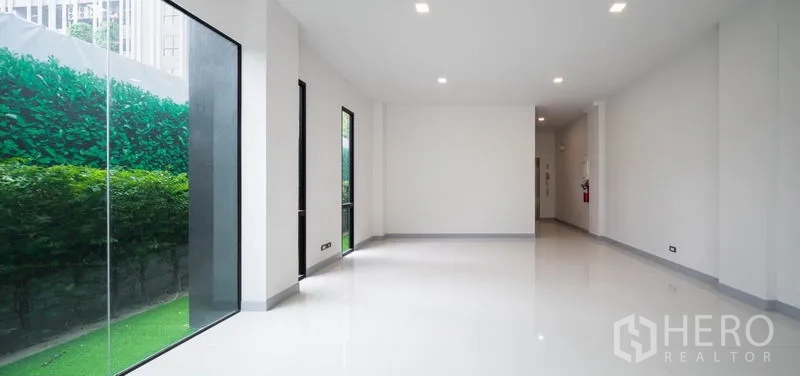 带办公室的家 出租在Bang Rak, Bangkok - 白色开放式室内，落地窗俯瞰绿色树篱。
